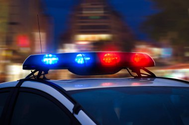 Police Car with Blue and Red Flashing Lights on the Street of Night City. Blurred background. clipart