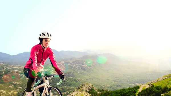 Mujer joven en Bright Pink Jacket Riding Road Bicicleta en Mountain Alpine Road. Concepto de Vida Saludable y Aventura . —  Fotos de Stock