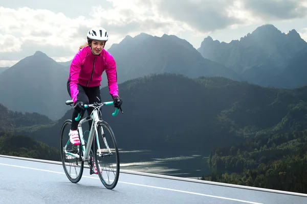 Mujer joven en Bright Pink Jacket Riding Road Bicicleta en Mountain Alpine Road. Concepto de Vida Saludable y Aventura . — Foto de Stock