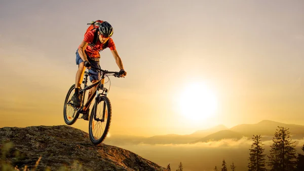 Radfahrer bei Sonnenaufgang in Rot mit dem Fahrrad den Felsen hinunter. Extremsport und Enduro-Konzept. — Stockfoto