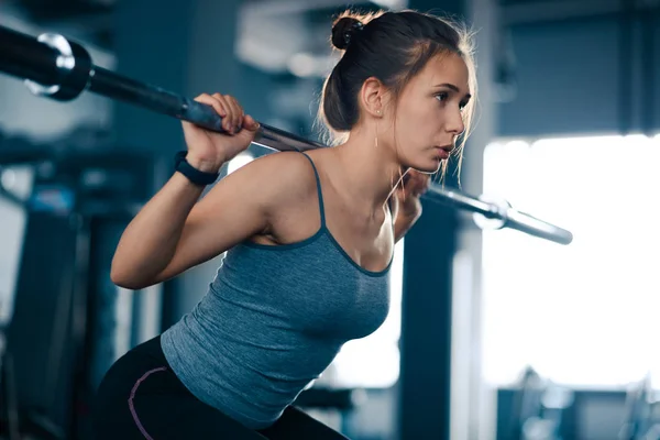 Attrayant jeune femme sportive faisant squats avec Barbell dans la salle de gym. Fitness et mode de vie sain . — Photo