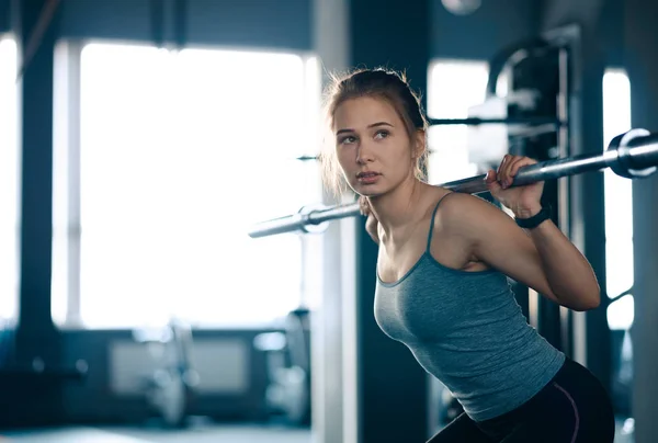 Atraktivní mladá sportovní žena dělá v tělocvičně squaty s Barbellem. Fitness a zdravý životní styl. — Stock fotografie