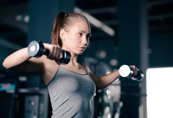 Attrayant jeune femme sportive haltères de levage dans la salle de gym. Fitness et mode de vie sain . — Photo