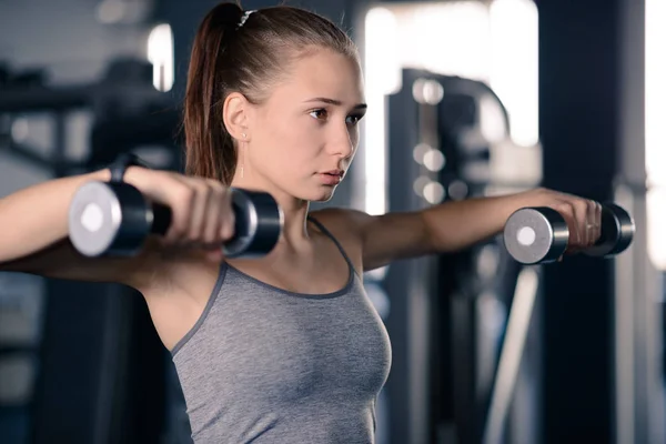Attrayant jeune femme sportive haltères de levage dans la salle de gym. Fitness et mode de vie sain . — Photo