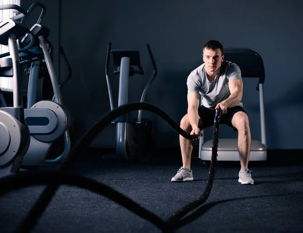 Muscolare uomo sta facendo battaglia corda Esercizio in palestra moderna fitness. CrossFit e concetto di stile di vita sano . — Foto Stock