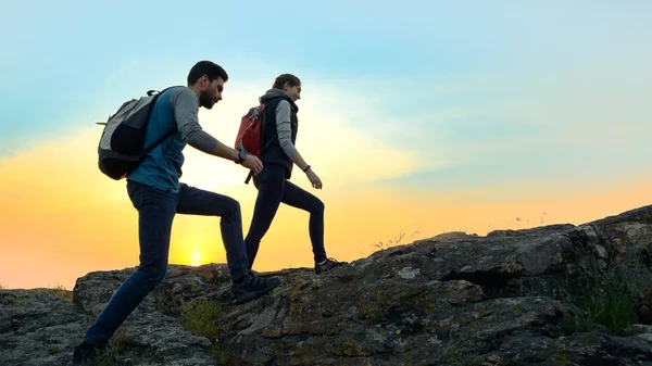 Young Happy Travelers Hiking with Backpacks on the Rocky Trail at Summer Sunset. Family Travel and Adventure Concept. — Stock Photo, Image