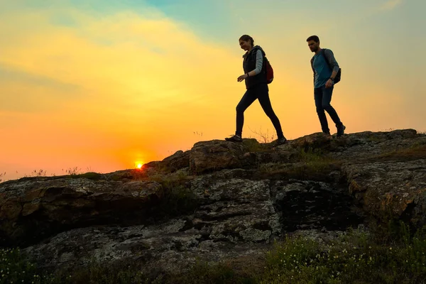 Young Happy Travelers Hiking with Backpacks on the Rocky Trail at Summer Sunset. Family Travel and Adventure Concept. — Stock Photo, Image