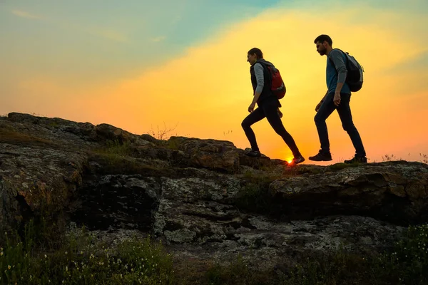 Young Happy Travelers Hiking with Backpacks on the Rocky Trail at Summer Sunset. Family Travel and Adventure Concept. — Stock Photo, Image