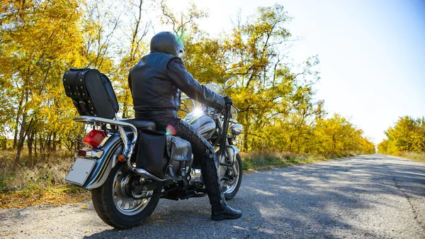 秋の道路にカスタムチョッパーバイクに乗るオートバイのドライバー。旅行と冒険のコンセプト. — ストック写真