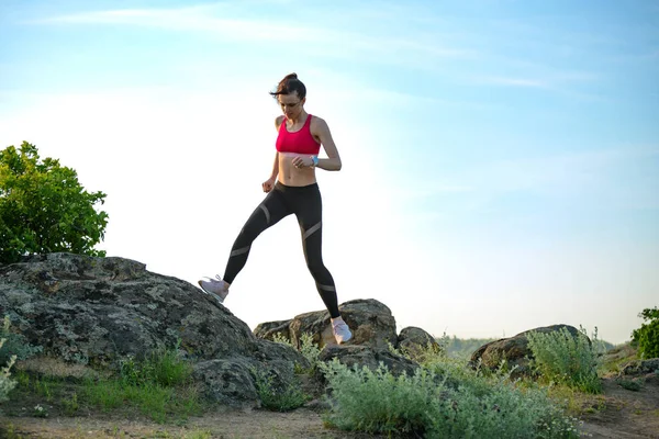 Joven hermosa mujer corriendo en el sendero de la montaña en la noche de verano caliente. Deporte y estilo de vida activo . — Foto de Stock