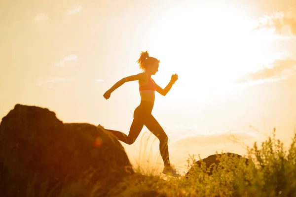 Νέα όμορφη γυναίκα τρέχει στο βουνό μονοπάτι στο ζεστό καλοκαιρινό ηλιοβασίλεμα. Αθλητισμός και ενεργός lifestyle. — Φωτογραφία Αρχείου