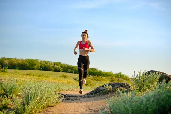 Νέα όμορφη γυναίκα τρέχει στο βουνό μονοπάτι στο ζεστό καλοκαίρι το βράδυ. Αθλητισμός και ενεργός lifestyle. — Φωτογραφία Αρχείου