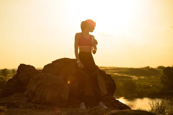 年轻女子休息和饮用水后 小径户外运行 在炎热美丽的夏季日落锻炼 运动与健康活跃生活理念 — 图库照片