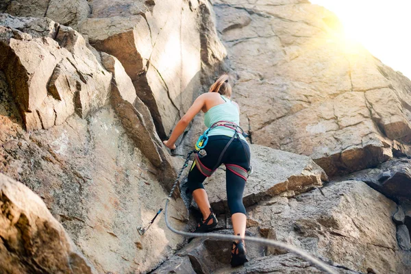 Schöne Frau beim Klettern auf einem Felsen in den Bergen. Abenteuer und Extremsportkonzept — Stockfoto