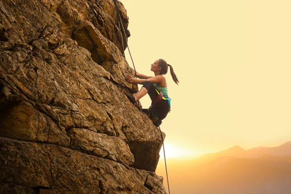 Beautiful Woman Climbing on the Rock at Foggy Sunset in the Mountains. Adventure and Extreme Sport Concept — Stock Photo, Image