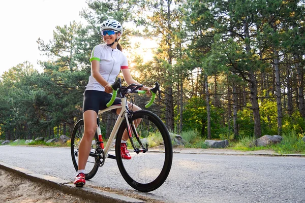 Retrato de una joven ciclista con bicicleta de carretera en el camino en el bosque de verano. Concepto de estilo de vida saludable . — Foto de Stock