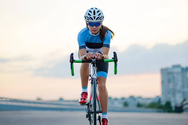 Mujer joven montando bicicleta de carretera en la calle libre en la ciudad al atardecer. Concepto de estilo de vida saludable y deporte . — Foto de Stock