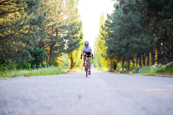 Giovane ciclista ciclista su strada Bicicletta sulla strada libera nella foresta a Hot Summer Day. Concetto di stile di vita sano . — Foto Stock