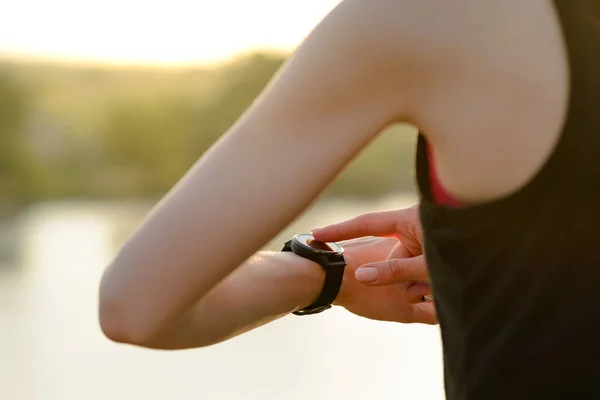 Mulher Runner descansando na trilha ao pôr do sol e usando Smartwatch. Fechar as mãos com relógio inteligente. Conceito Desportivo . — Fotografia de Stock