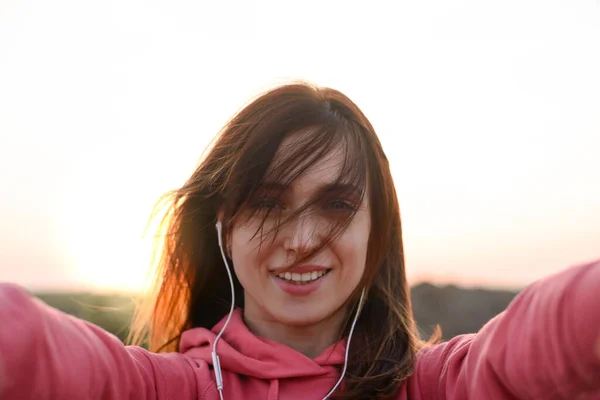 Smuk smilende pige runner Tag Selfie fra hænder med telefon udendørs om sommeren aften. Sund livsstil koncept . - Stock-foto