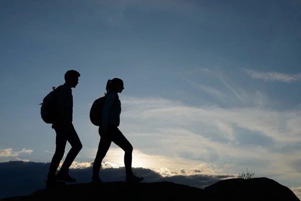 Young Happy Travelers Hiking with Backpacks on the Rocky Trail at Summer Sunset. Family Travel and Adventure Concept. — Stock Photo, Image