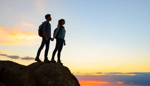 Пара молодых путешественников, стоящих на вершине скалы на Саммер Сансет. Семейные путешествия и отдых — стоковое фото