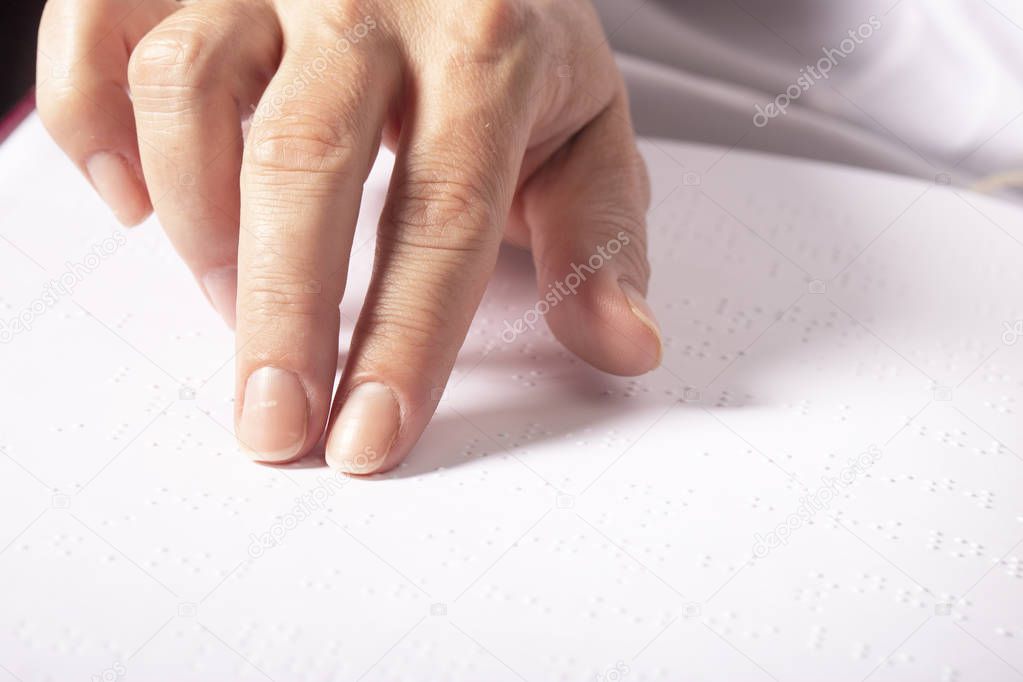Blind woman read book written in Braille. Close up finger touch to braille