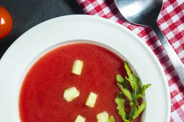 Gros plan d'une assiette de soupe gaspacho avec des tranches de tomate, concombre et oignon, avec des feuilles de persil — Photo