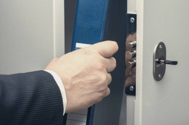 İş adamı dosyayı kasaya koyar.