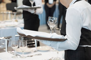 Garson üniformalı, şarap kadehi servis ediyor.