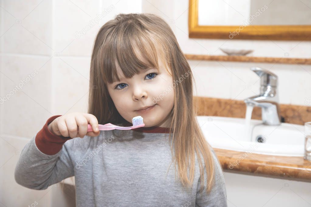 little cute girl wearing a bathrobe brushing her teeth