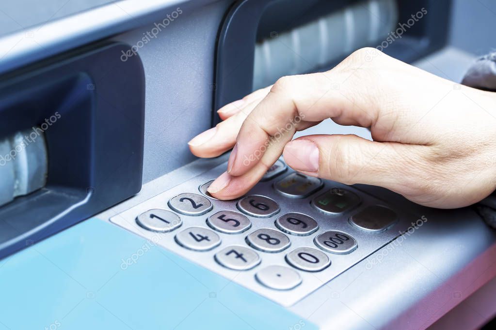 Close-up of woman s hand introducing pin code at ATM machine for cash withdrawal