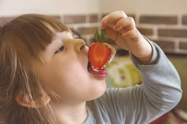 クリームとイチゴを食べる少女. — ストック写真