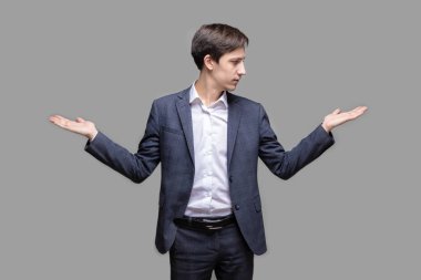 Yakışıklı genç adam onun avuç içi üzerinde iki ürün arasında bir seçim yapmak isteyen takım elbiseli gülümseyen portresi