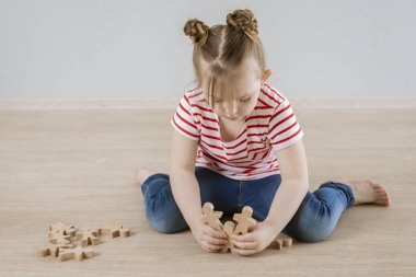 Çocuktaki yumuşak becerilerin gelişimi. Tahta figürlerle oynayan kız.