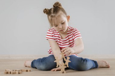 Çocuktaki yumuşak becerilerin gelişimi. Tahta figürlerle oynayan kız.