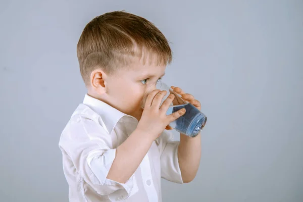 Menino bonito bebe água de um copo . — Fotografia de Stock