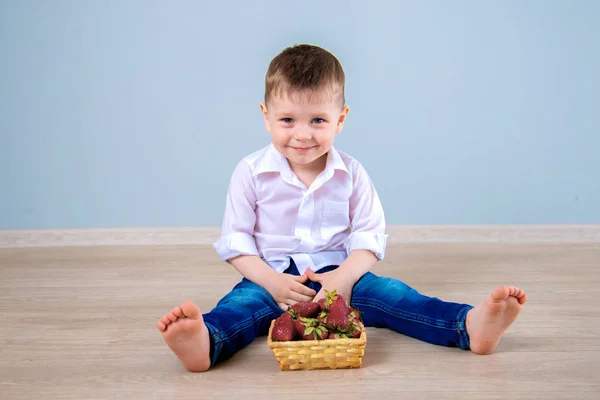 Meninos sentam-se no chão em casa com uma cesta de morangos — Fotografia de Stock