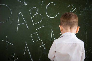 Küçük bir çocuk okul yönetim kurulunda duruyor..