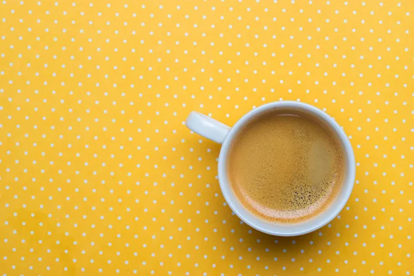 Uma xícara de café em um fundo amarelo bolinhas . — Fotografia de Stock