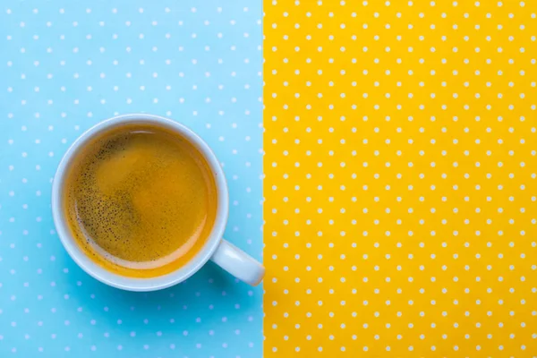 Xícara de café em um fundo de bolinhas amarelo e azul . — Fotografia de Stock