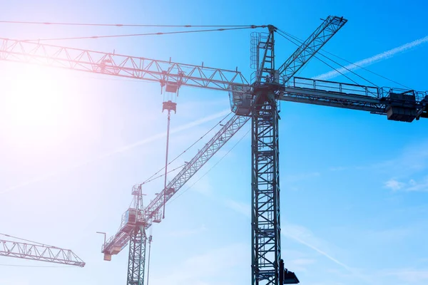 Big tower cranes against the blue sky. Background image of construction equipment close-up with copy space. — Stock Photo, Image
