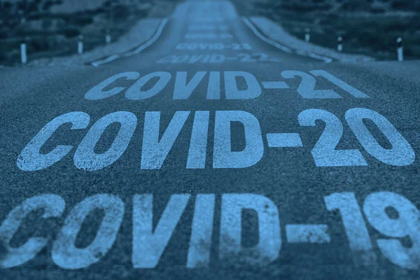 Deserted highway with the text COVID-19, COVID-20, COVID-21 and so on. The concept of new world pandemics — Stock Photo, Image
