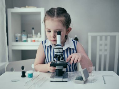 Küçük kız laboratuarında kimyasal ve biyolojik ürünlerle bilimsel deneyler yapıyor..