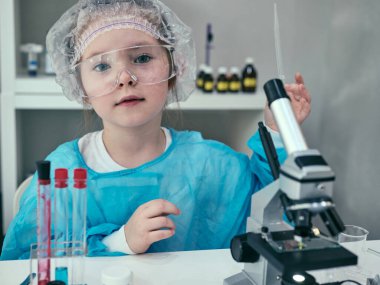 Küçük kız laboratuarında kimyasal ve biyolojik ürünlerle bilimsel deneyler yapıyor..