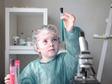 Evdeki masasında mikroskoba bakan sevimli küçük kız. Genç bilim adamı laboratuarında deneyler yapıyor.. 