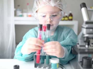 Evdeki masasında mikroskoba bakan sevimli küçük kız. Genç bilim adamı laboratuarında deneyler yapıyor.. 