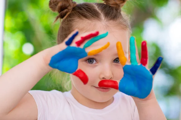 Malá holčička s dlaněmi potřísněnými barvou. Emoce šťastného dětství a tvořivosti. — Stock fotografie
