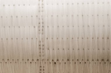 Uçak gövdesinin eski gümüş metal yüzeyinde perçin var.