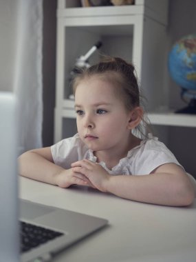 Evde dizüstü bilgisayar kullanan tatlı bir kız. Eğitim, online çalışma, evde öğrenim gören kız arkadaşlarıyla internet üzerinden iletişim kuruyor. Çocuklar uzaktan öğreniyor. 